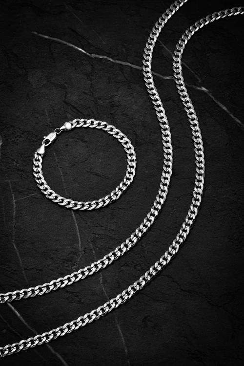 Free Stylish silver chain and bracelet set on a dark textured background, perfect for fashion lovers. Stock Photo
