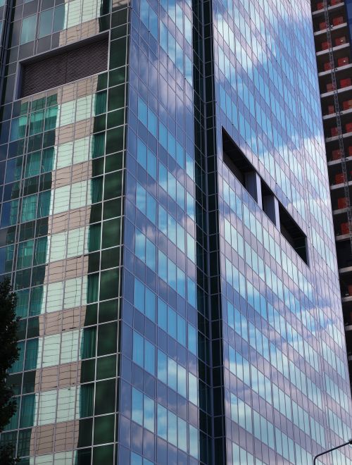 Free A glass skyscraper reflecting clouds and blue sky, showcasing urban architecture. Stock Photo