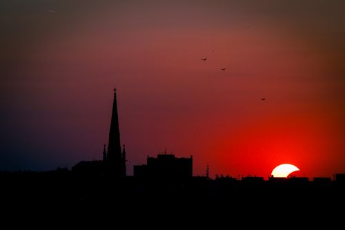 Free Silhouette of Novi Sad skyline during sunset with half-visible sun. A vibrant and moody urban landscape. Stock Photo
