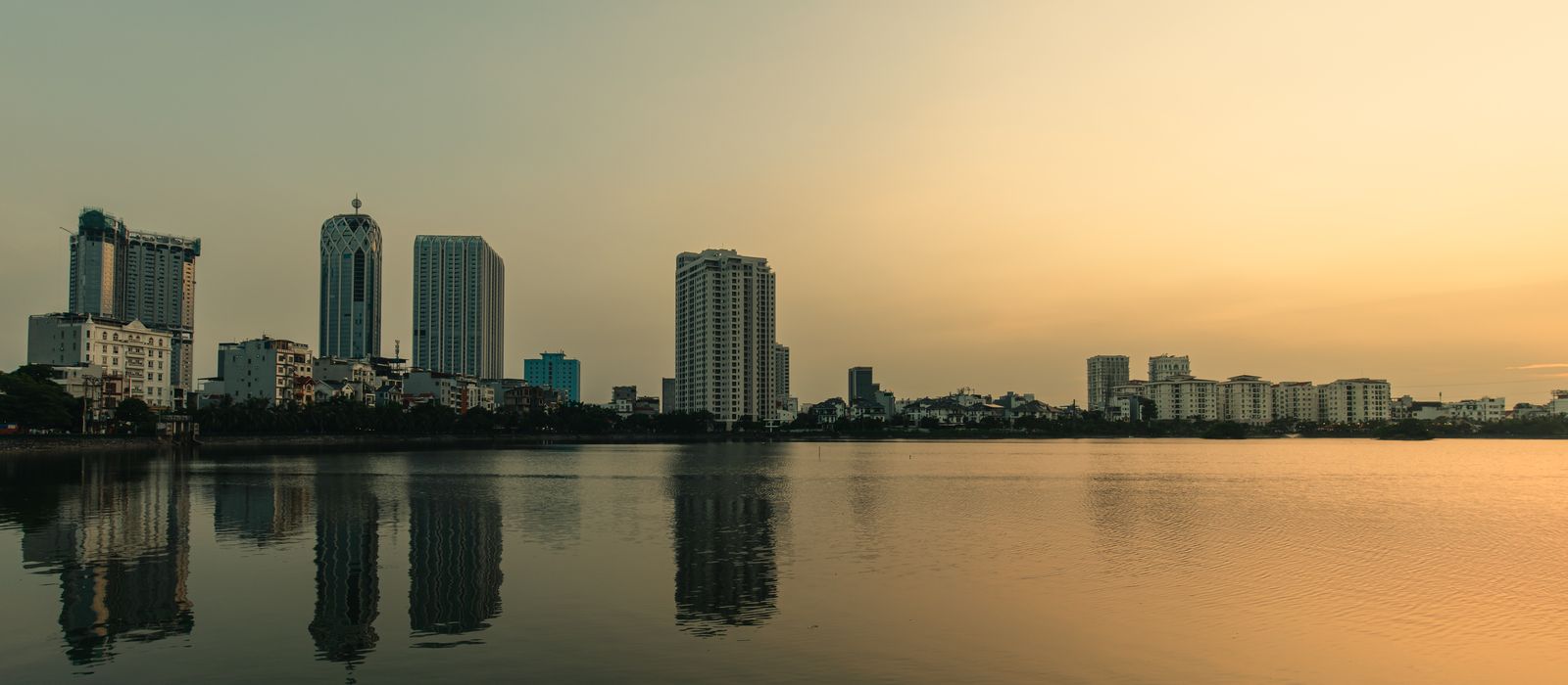 Serene view of Haiphong skyline with buildings reflecting in calm dusk waters. Peaceful cityscape. — flights from Hanoi to Haiphong