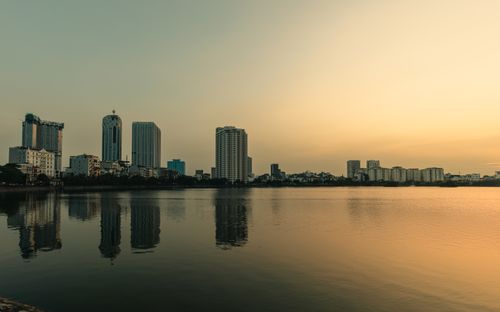 Free Serene view of Haiphong skyline with buildings reflecting in calm dusk waters. Peaceful cityscape. Stock Photo