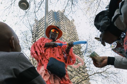 Colorful street performer creating balloon animals for crowd in lively Johannesburg setting.