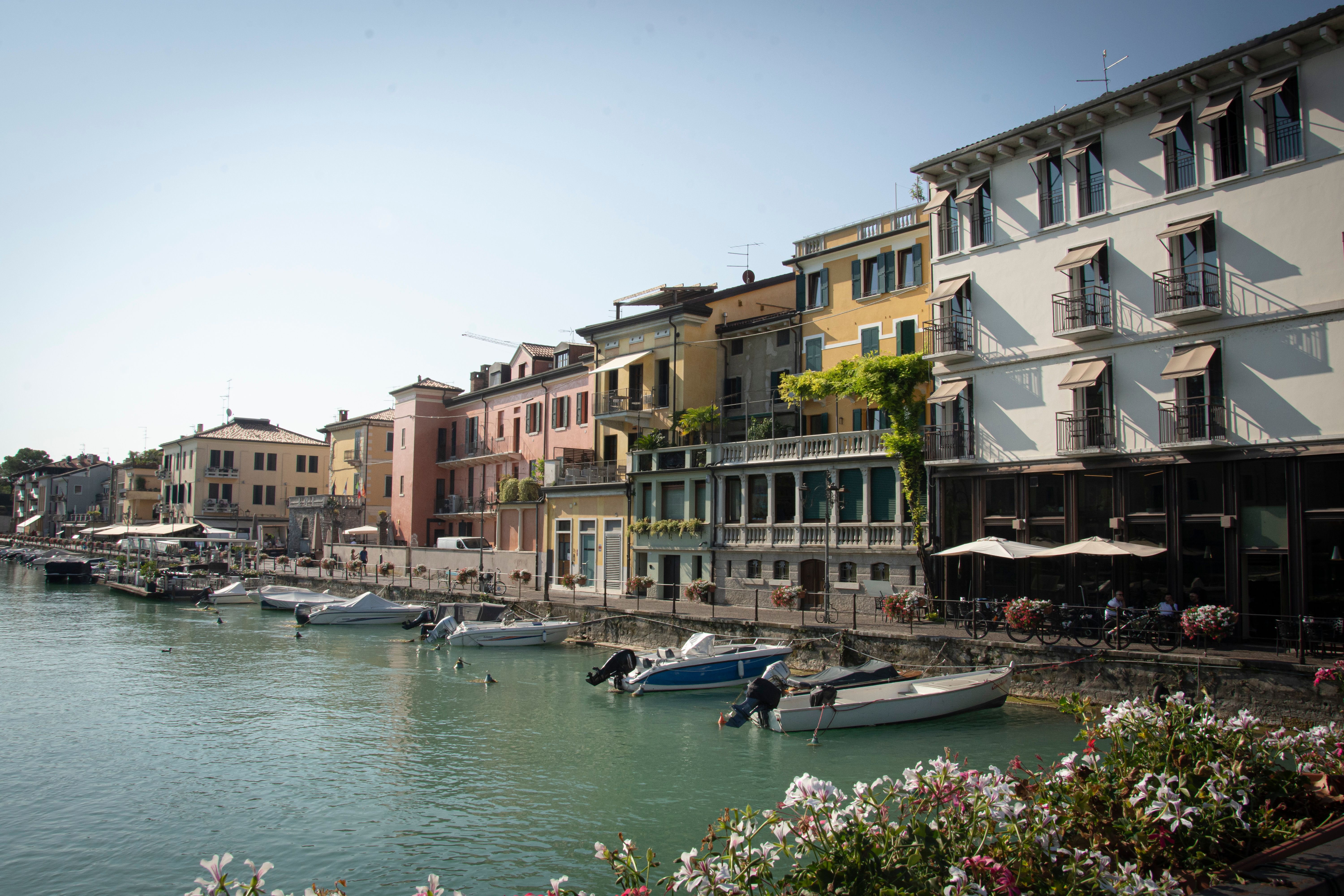 Picturesque waterfront with colorful buildings and boats in Peschiera del Garda, Italy.