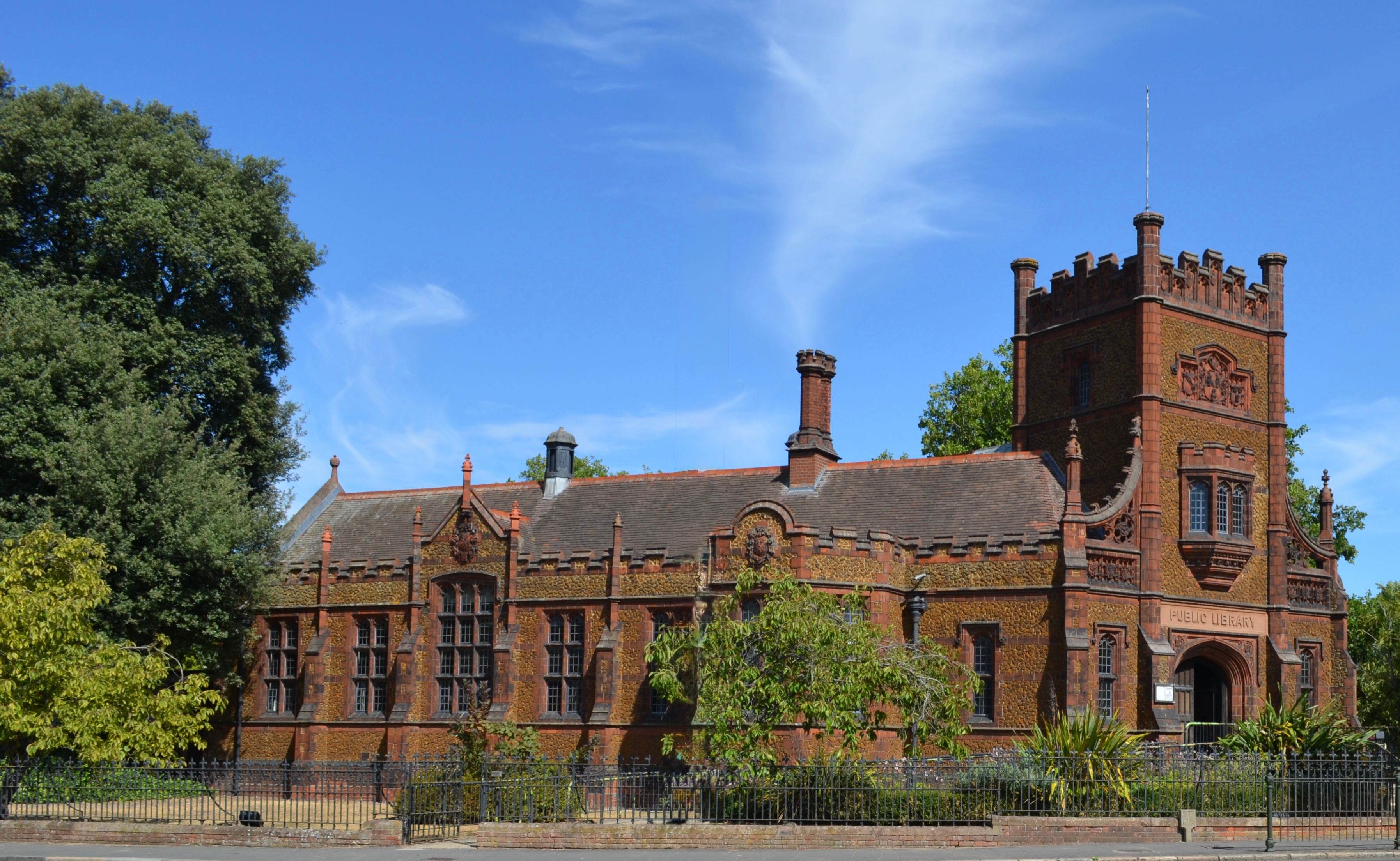 Victorian-era public library with red-brick façade under clear blue sky.