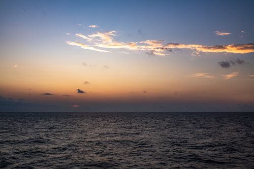 Free Peaceful sunset over the ocean with colorful sky and calm waves. Stock Photo