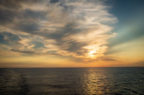Free Gorgeous sunset over the ocean with dramatic clouds and a tranquil sea. Stock Photo