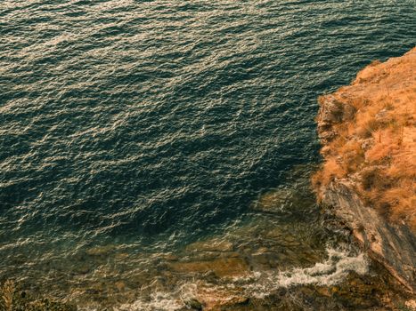 A stunning view of a rugged coastal cliff meeting the tranquil ocean waters.
