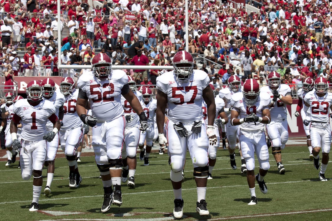 Football players walking across the field in front of a crowd