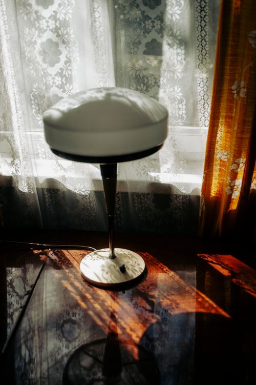 Free A modern bar stool basking in ambient sunlight, casting shadows through floral curtains. Stock Photo