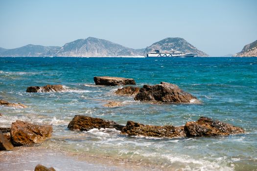 Ferry cruising near rocky shore with clear blue waters in Skopelos, Greece.