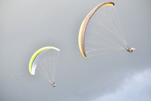 Free Paragliders enjoying extreme sports in Bir, Himachal Pradesh against a cloudy sky. Stock Photo