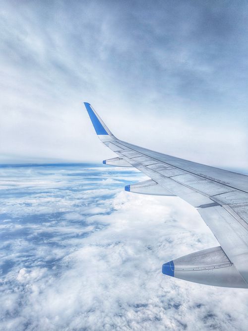 Free Airplane wing soaring above fluffy clouds with a serene sky view, showcasing air travel and exploration. Stock Photo