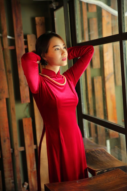 Woman in Red Long Sleeve Dress Standing Looking Out the Window