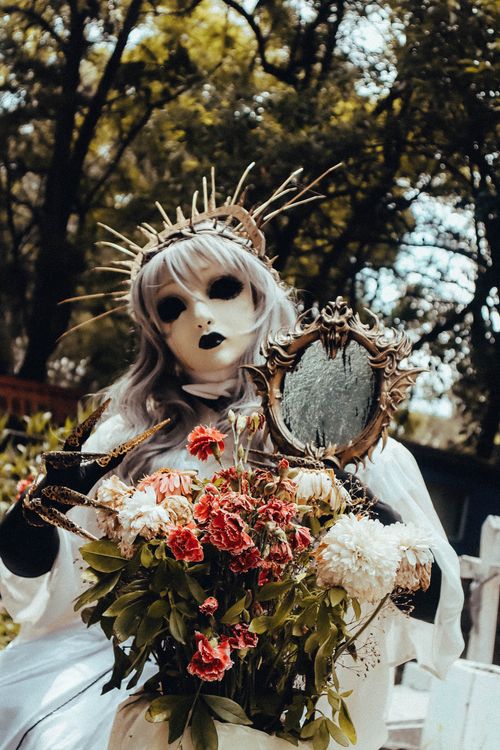 Free Dramatic scene of a Gothic figure holding an ornate mirror in a forest setting. Stock Photo