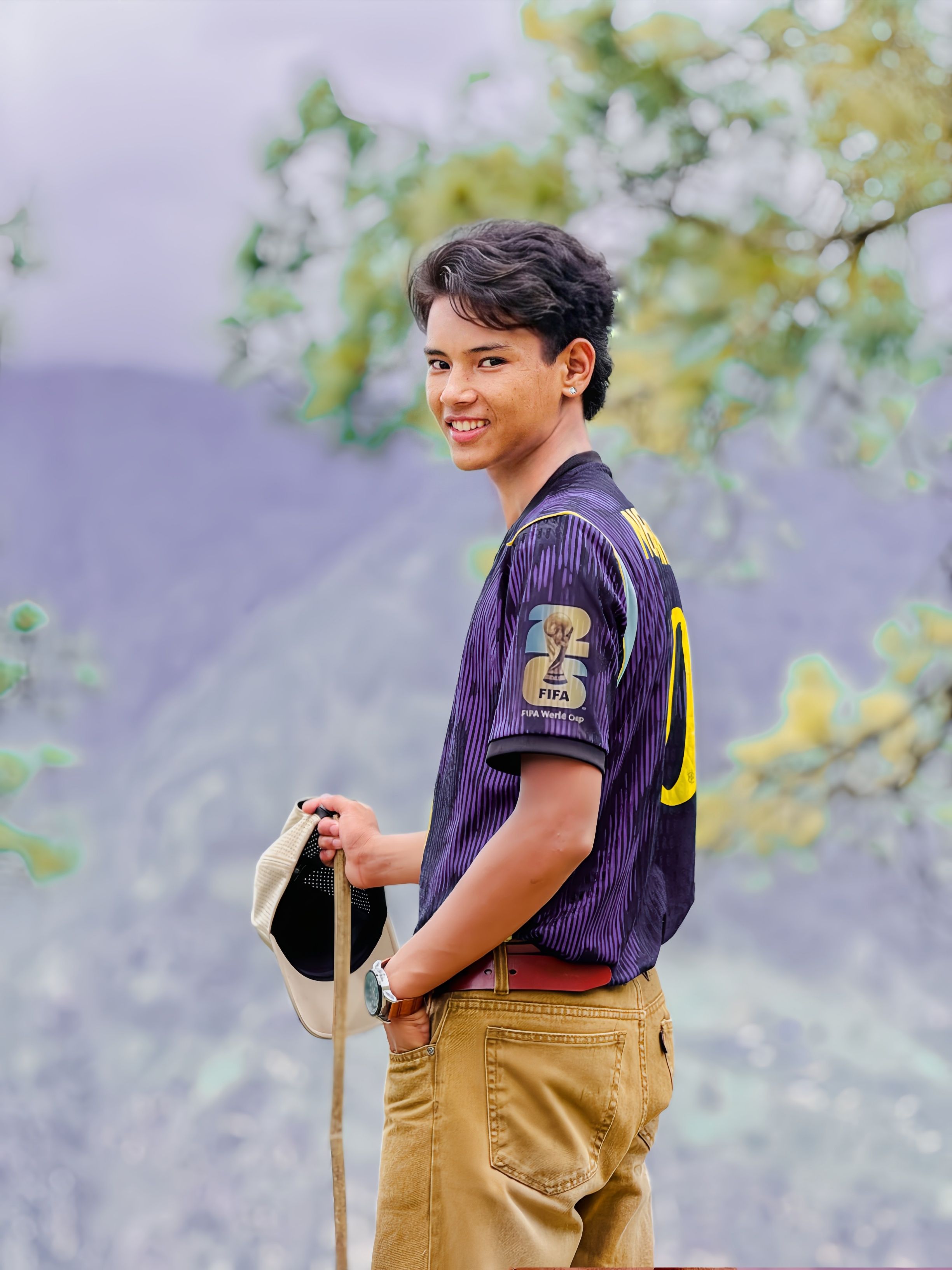 Teenage boy smiling in a nature setting holding a cap. Captured on Snapseed 2.0.