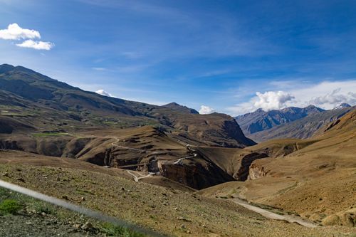 Free Breathtaking view of winding roads through a vast mountain landscape under a clear blue sky. Stock Photo