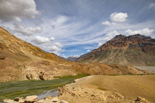 Free Stunning view of rugged mountain terrain under a vibrant blue sky with fluffy clouds. Stock Photo