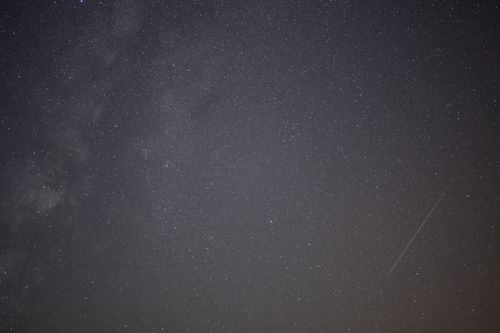 Free A breathtaking view of the night sky filled with stars and a visible meteor streak. Stock Photo