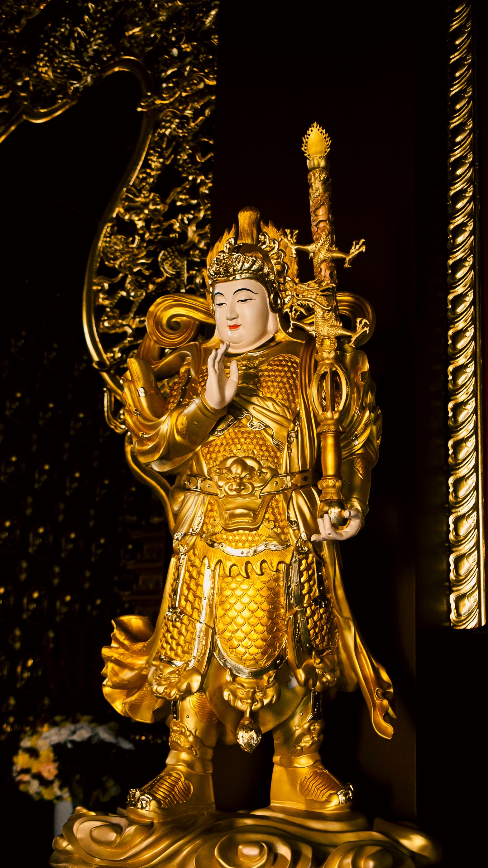 A detailed golden Buddha statue adorned with ornate armor, located in a temple in Ho Chi Minh City, Vietnam.
