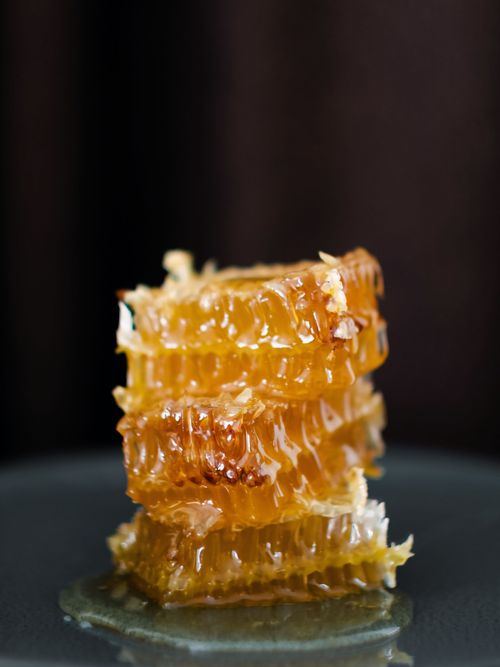Free Stacked golden honeycomb dripping honey on a dark background. Stock Photo