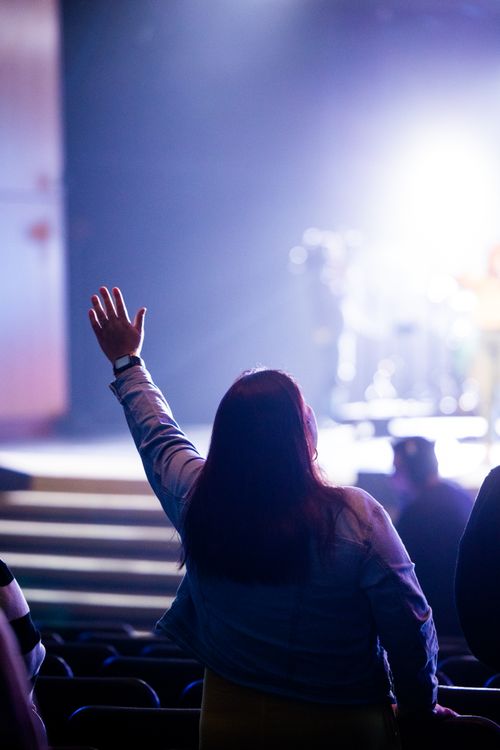 Free A woman raises her hand in a well-lit indoor environment, seemingly engaged in an event. Stock Photo