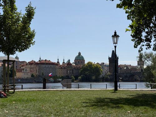 Free A picturesque view of Prague's historic architecture and riverfront on a sunny day, featuring iconic landmarks. Stock Photo