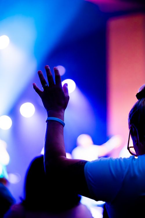 Free Dynamic concert with vibrant lights and a raised hand in a crowd, capturing the energy and atmosphere. Stock Photo