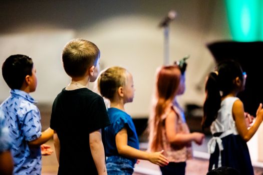 Children gathered indoors, attending an event, captured in a candid moment.