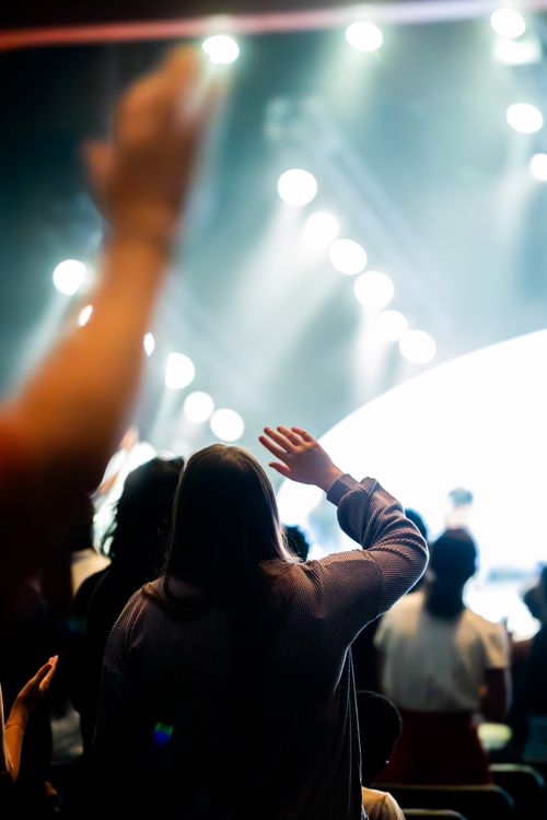 Free Energetic crowd with raised hands enjoying a lively concert performance, vibrant stage lights. Stock Photo