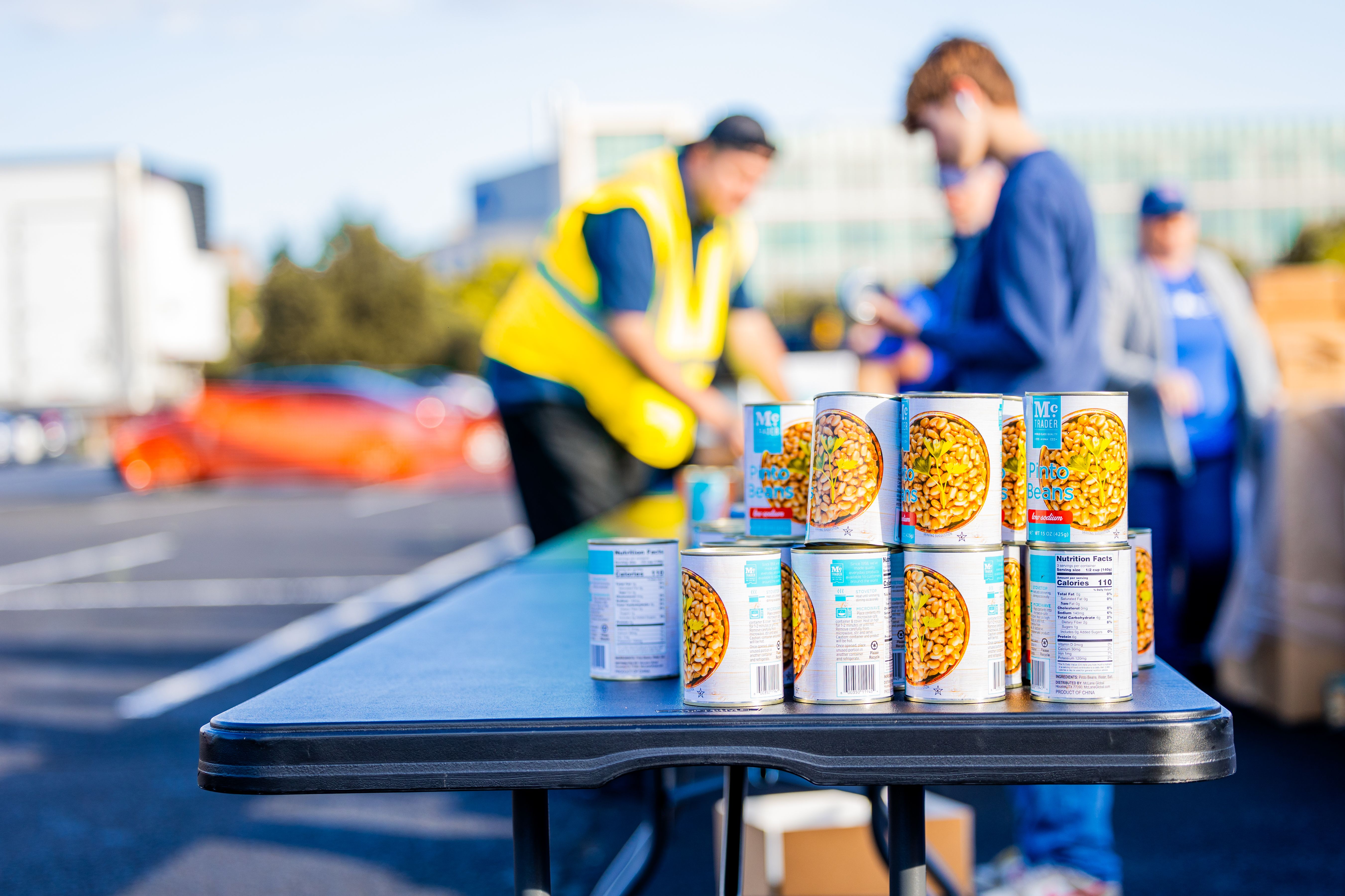 地域住民が屋外で食料を配布するイベントで、テーブルの上に並べられた缶詰。
