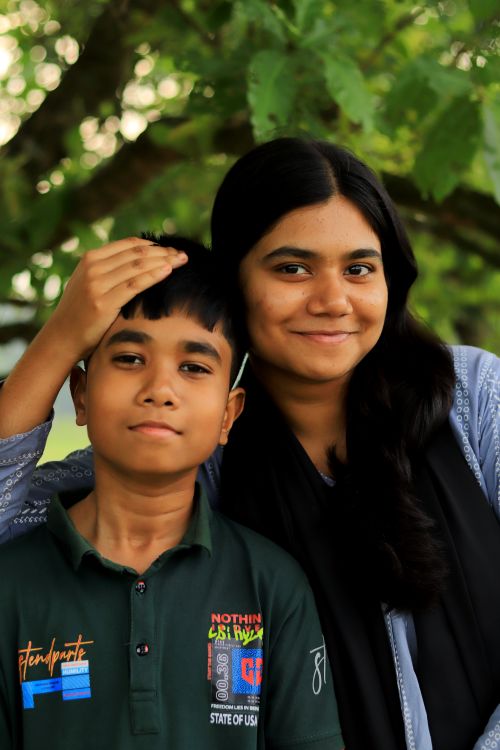 Free Portrait of a brother and sister under a tree, enjoying a sunny day and showcasing sibling bond. Stock Photo