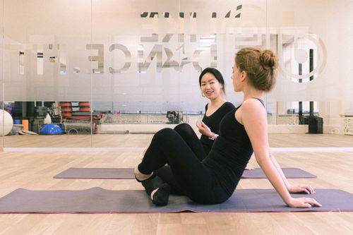 Free Two women in a fitness studio discussing exercises on mats. Relaxed training atmosphere. Stock Photo