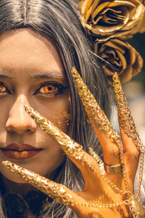 Free Gothic-inspired cosplay featuring golden artistic makeup and elaborate accessories. Stock Photo