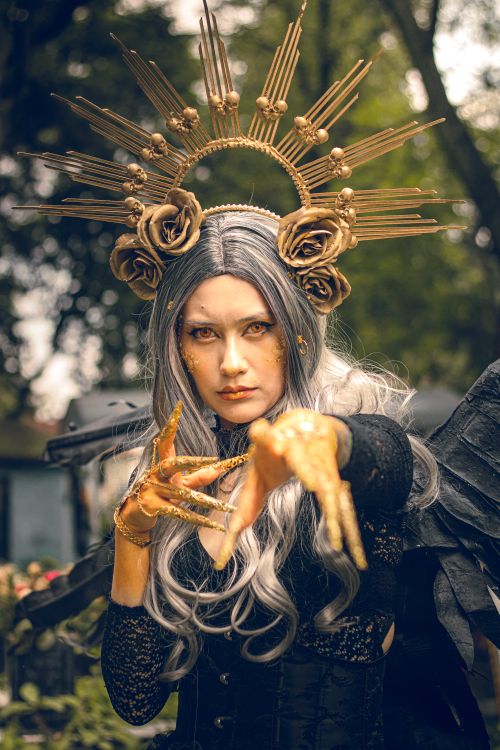 Free Gothic cosplay character with striking makeup and wings in a Mexican cemetery setting. Stock Photo