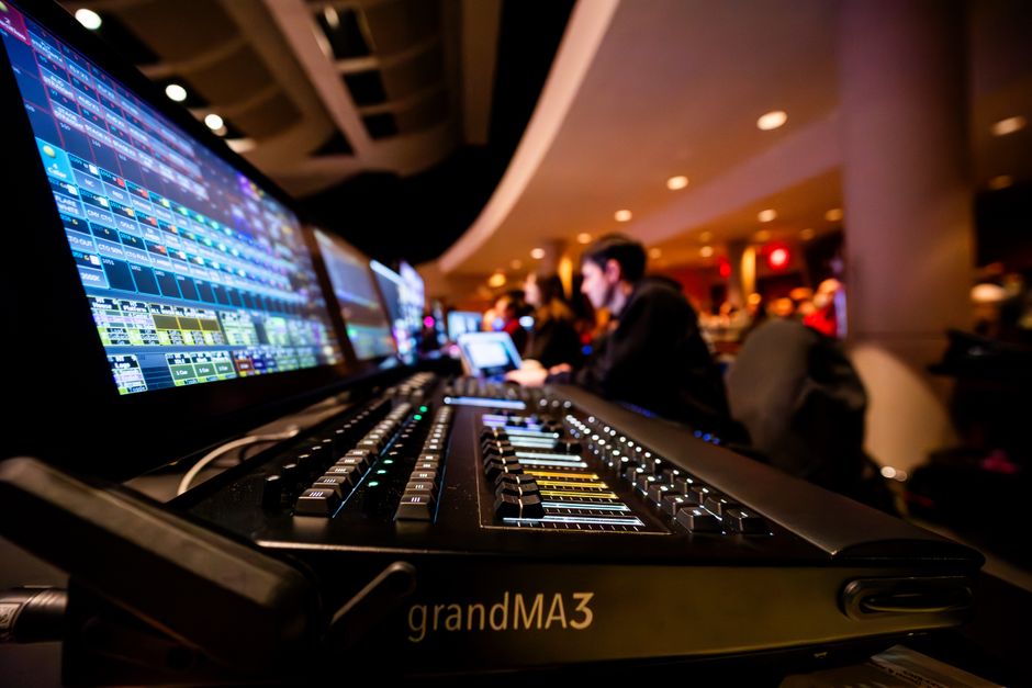 活気あふれる屋内イベント会場に設置されたgrandMA3照明コンソールのクローズアップ写真。