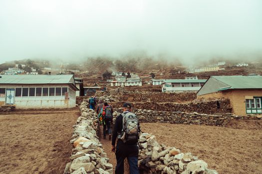 Group of trekkers on a foggy day exploring a remote Himalayan village, showcasing traditional architecture.