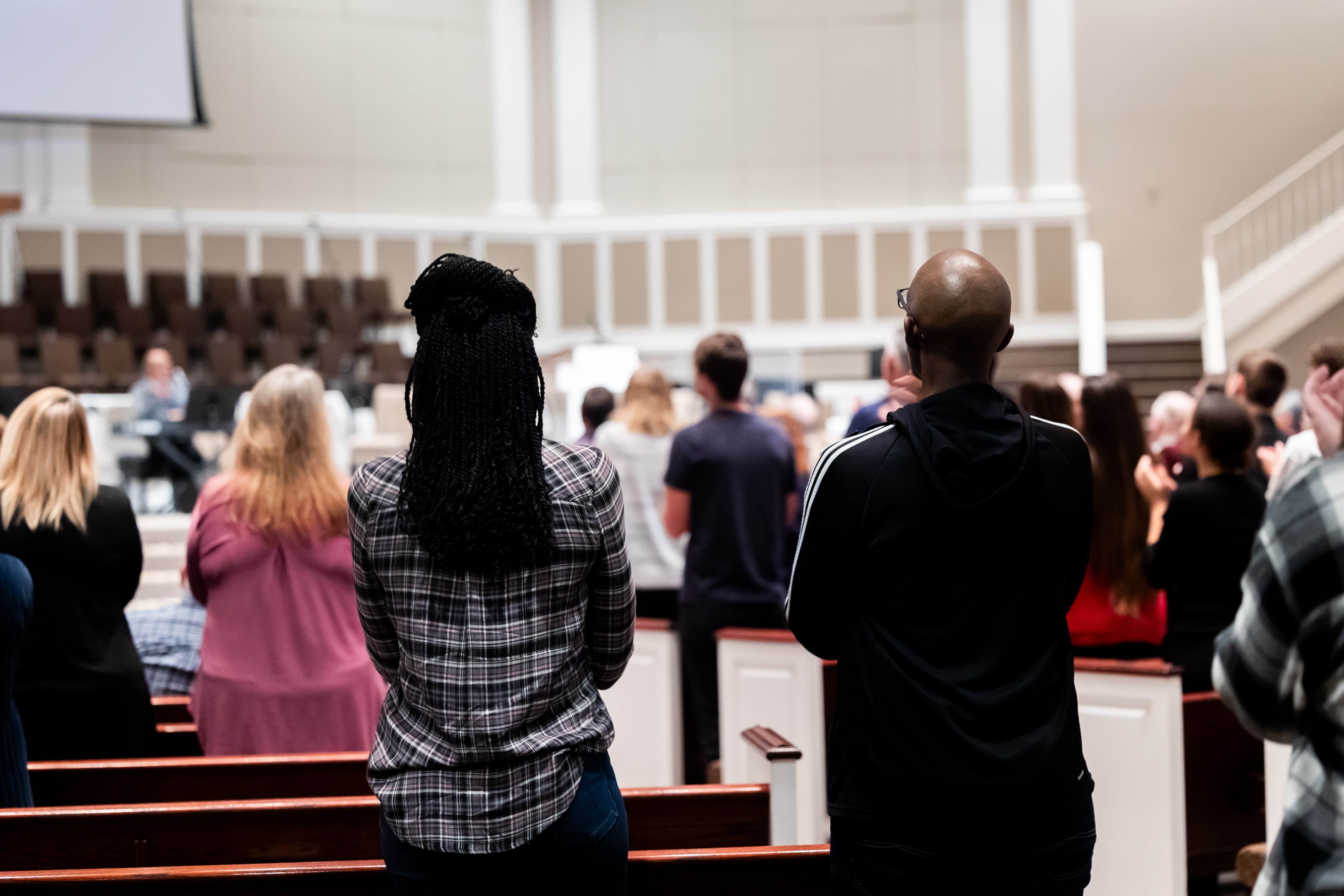 People attending a communal gathering in a church, viewed from behind, creates a sense of community and connection.