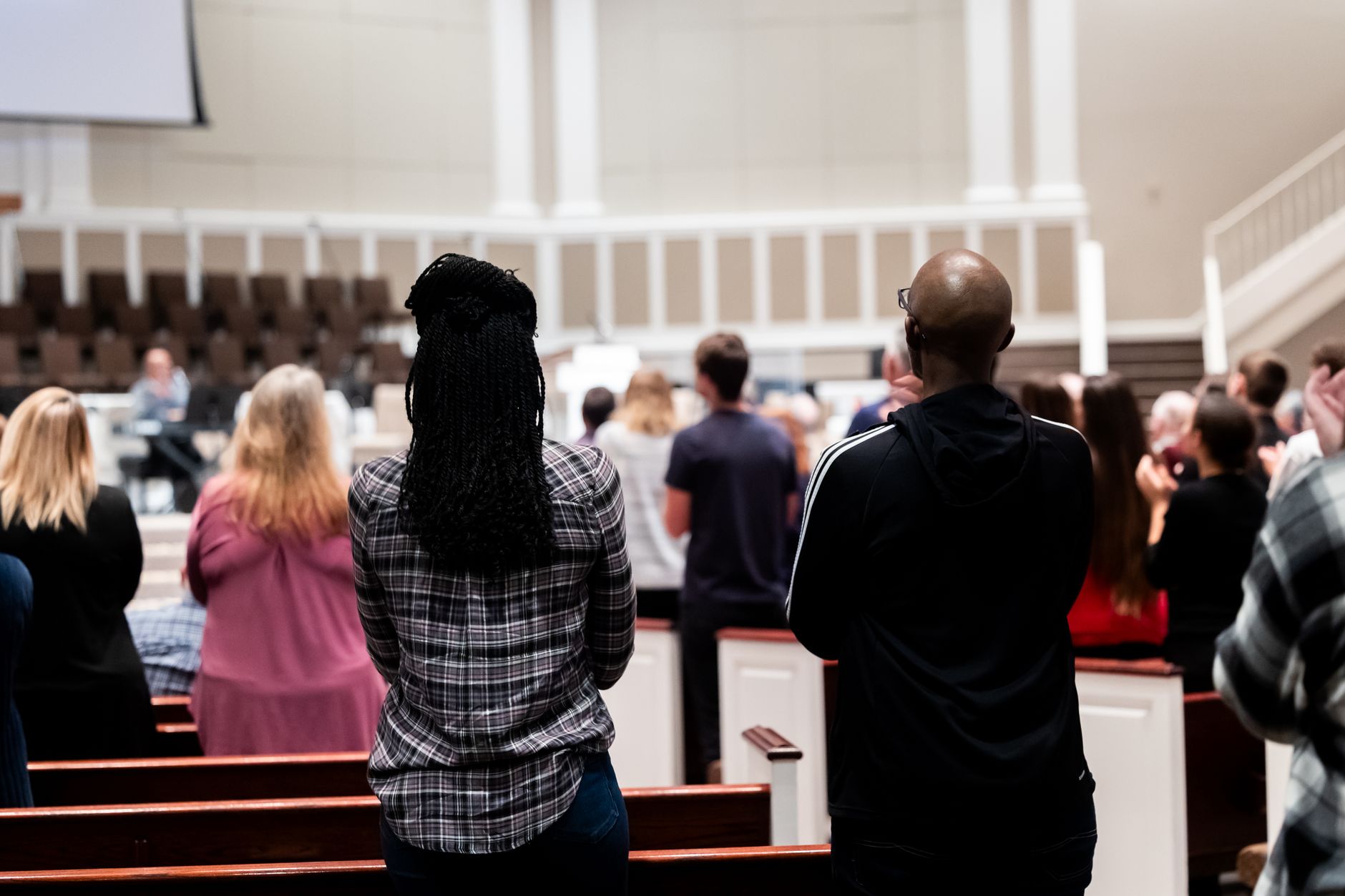 People attending a communal gathering in a church, viewed from behind, creates a sense of community and connection.