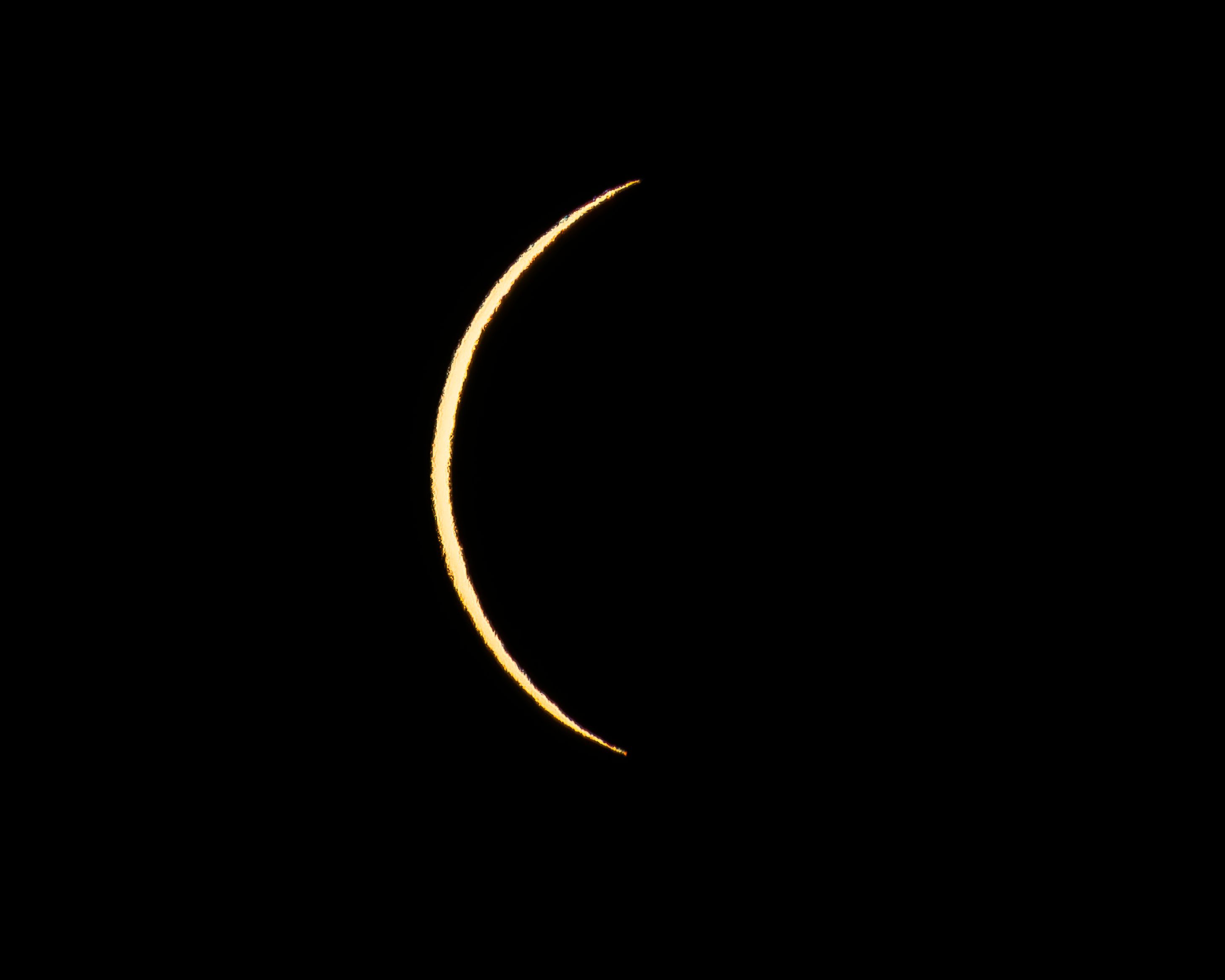 A vibrant crescent moon sharply outlined against a deep black night sky.