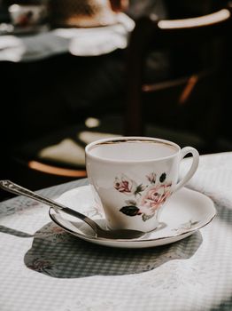 Charming porcelain teacup with floral patterns elegantly placed on a sunlit table setting.