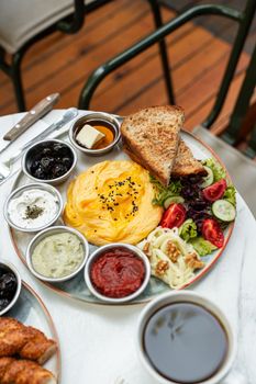 Appetizing brunch platter with eggs, toast, and various condiments on a wooden deck.