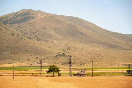 Free Expansive arid landscape featuring power lines and hills under a clear summer sky. Stock Photo
