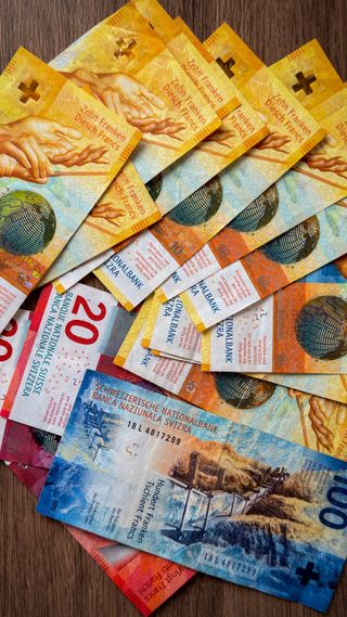 Overlapping Swiss-franc banknotes on a wooden surface