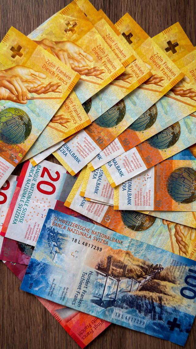 Overlapping Swiss-franc banknotes on a wooden surface