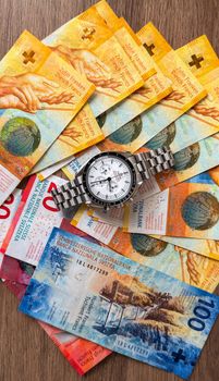 Luxury watch placed over a spread of Swiss Franc banknotes, symbolizing wealth and time value.