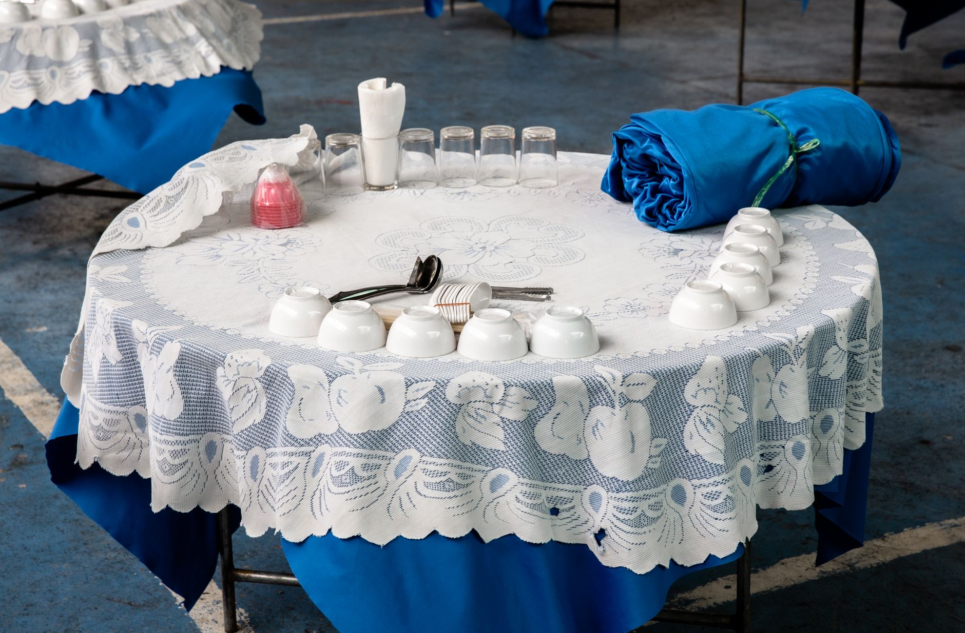 A beautifully arranged table with lace tablecloth and teacups, ready for service.