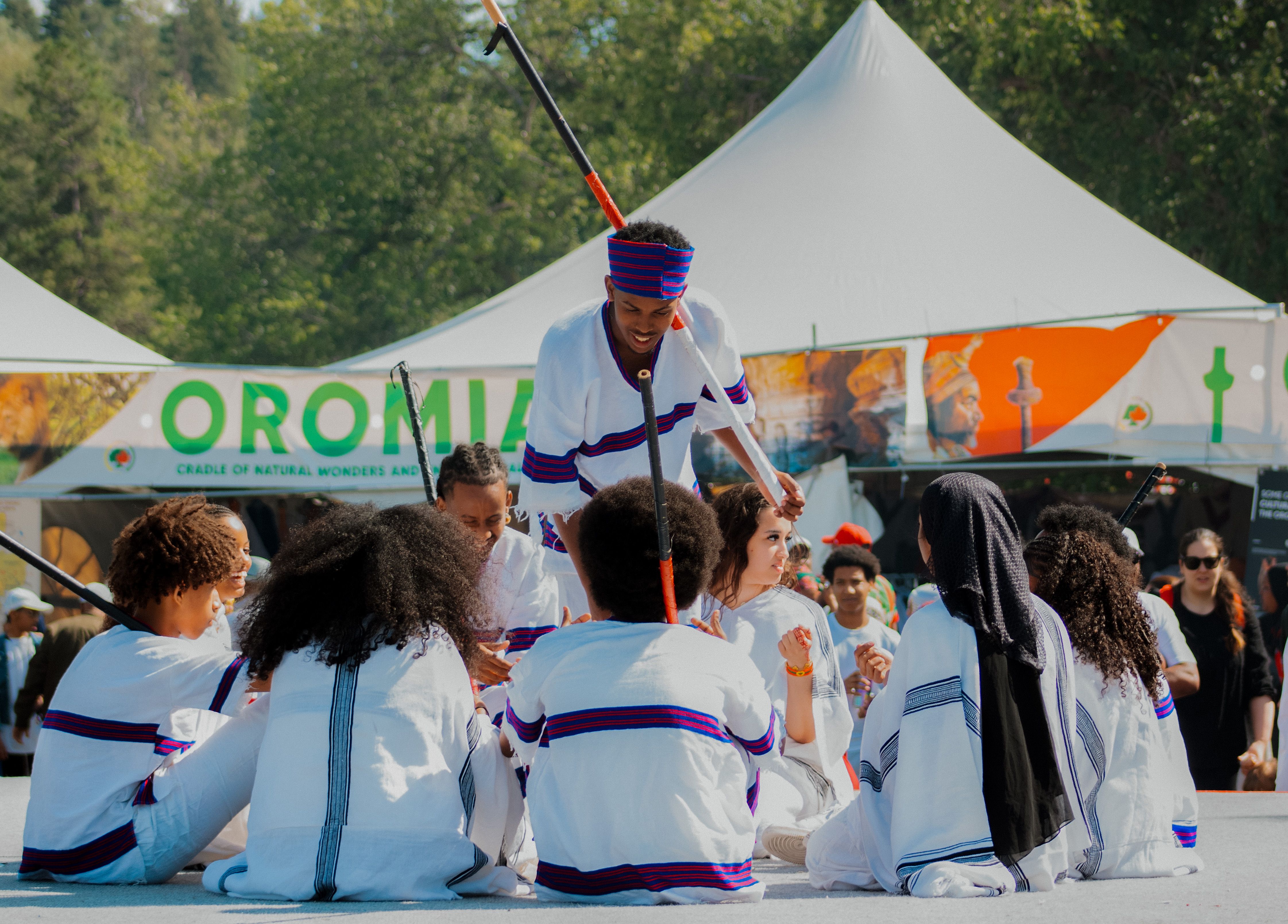 Group of people in traditional attire performing at Oromia cultural festival outdoors.