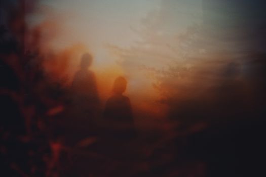 Ethereal silhouettes with a warm, abstract sunset background creating a dreamy atmosphere.