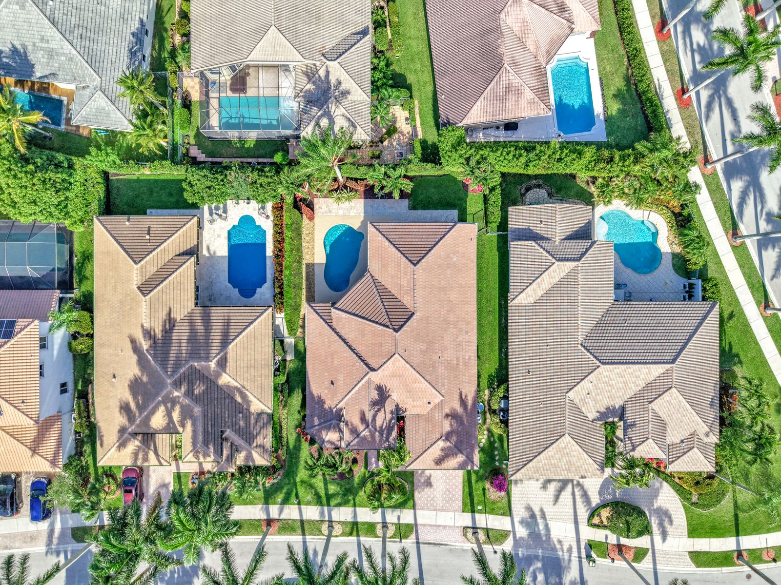 Aerial view of tile roof homes with screened pools in a gated West Boca Raton community