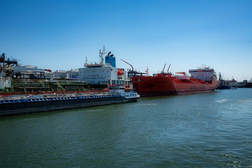 Free Cargo ships and tankers docked at an industrial port under a clear blue sky. Stock Photo
